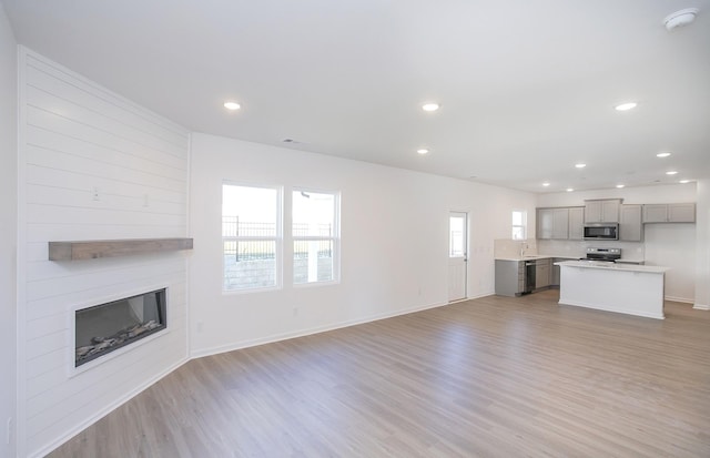 unfurnished living room with recessed lighting, a sink, a fireplace, and light wood finished floors