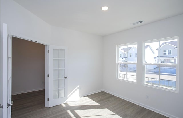 spare room featuring visible vents, baseboards, and wood finished floors