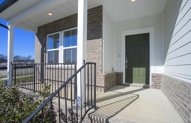 view of exterior entry with covered porch and brick siding