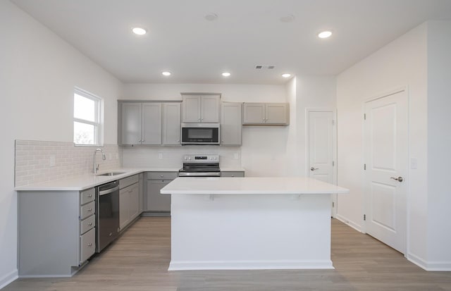 kitchen with stainless steel appliances, gray cabinets, visible vents, backsplash, and a sink