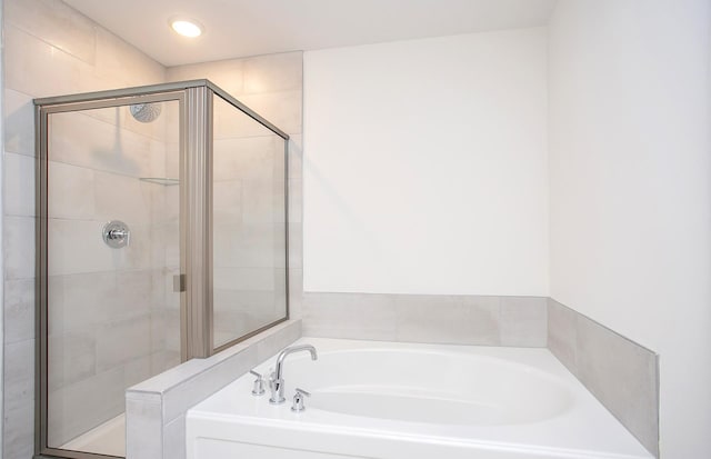 bathroom with a stall shower, a bath, and recessed lighting