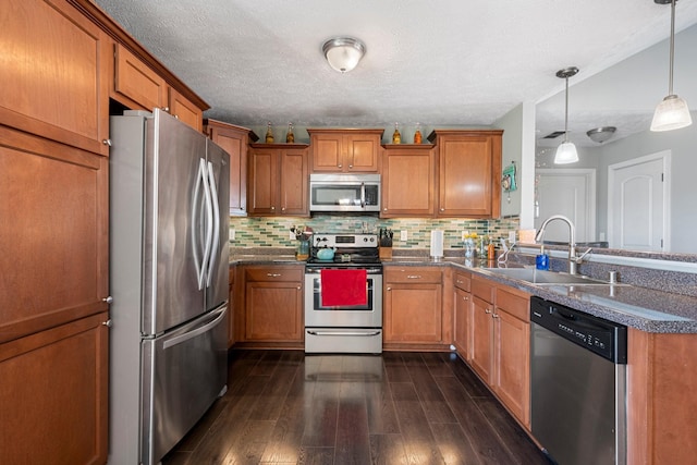 kitchen with sink, appliances with stainless steel finishes, dark hardwood / wood-style floors, pendant lighting, and backsplash