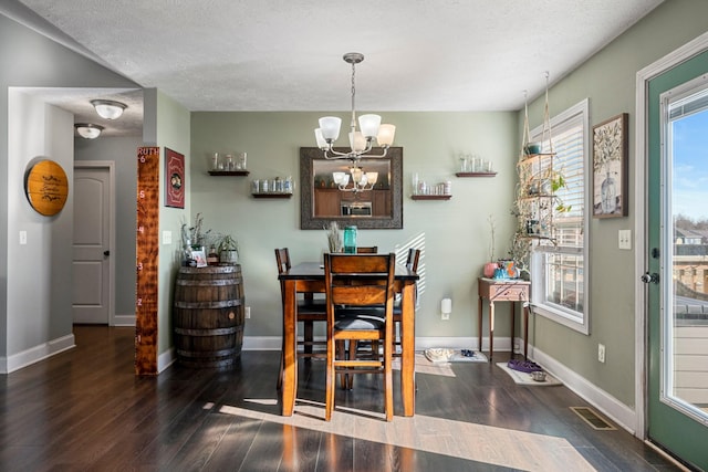 dining space featuring dark hardwood / wood-style flooring, a textured ceiling, and a notable chandelier