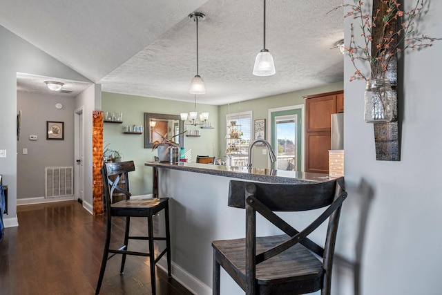 kitchen featuring sink, a breakfast bar area, hanging light fixtures, dark hardwood / wood-style floors, and vaulted ceiling