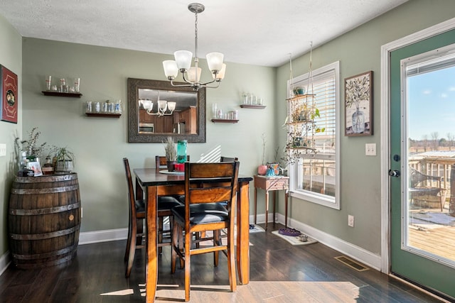 dining room featuring dark hardwood / wood-style flooring, a notable chandelier, and a textured ceiling