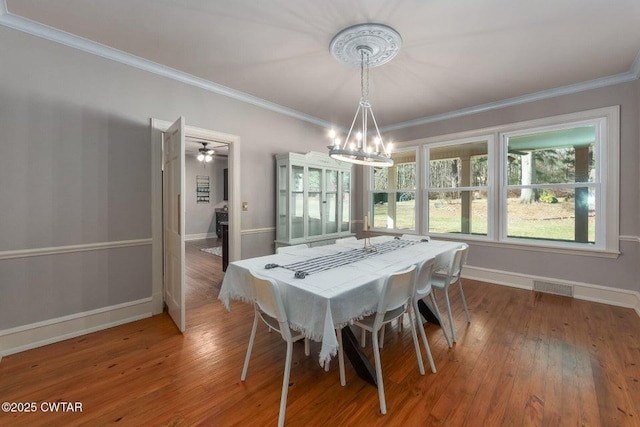 dining space with crown molding, wood-type flooring, and a notable chandelier