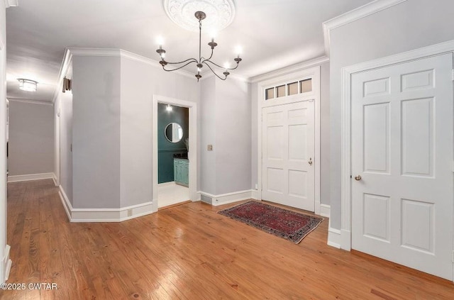 foyer entrance with wood-type flooring, ornamental molding, and a chandelier