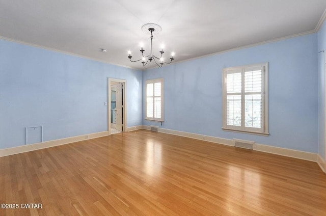 empty room featuring crown molding, a healthy amount of sunlight, a notable chandelier, and light hardwood / wood-style flooring