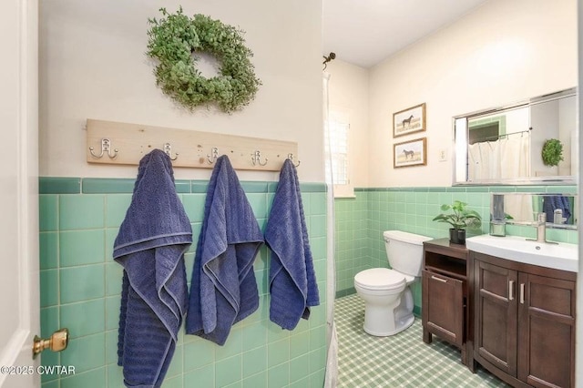 bathroom with tile walls, vanity, tile patterned flooring, and toilet