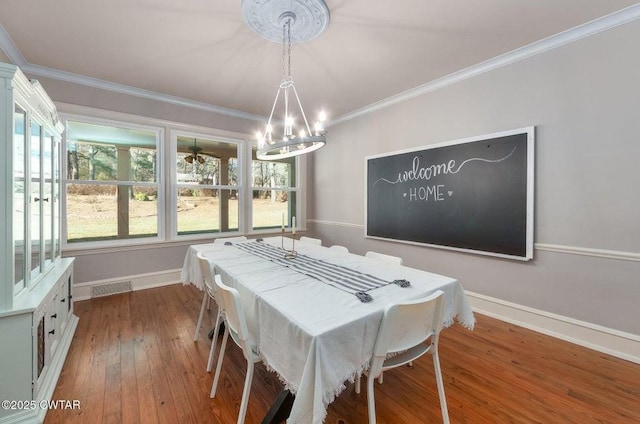 dining space with a notable chandelier, crown molding, and wood-type flooring