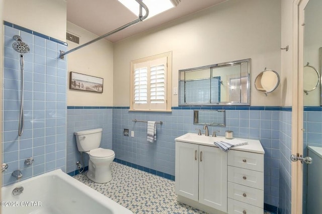 full bathroom featuring tiled shower / bath, tile walls, vanity, and toilet