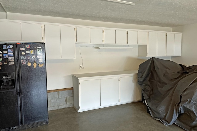 kitchen featuring white cabinetry, black refrigerator with ice dispenser, and a textured ceiling