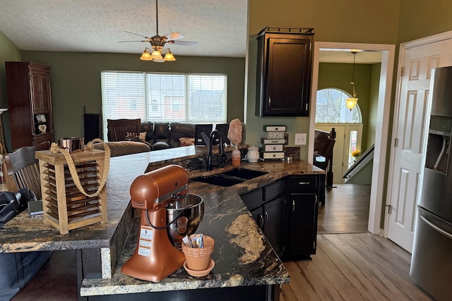 kitchen featuring sink, stainless steel fridge with ice dispenser, a textured ceiling, light hardwood / wood-style flooring, and pendant lighting