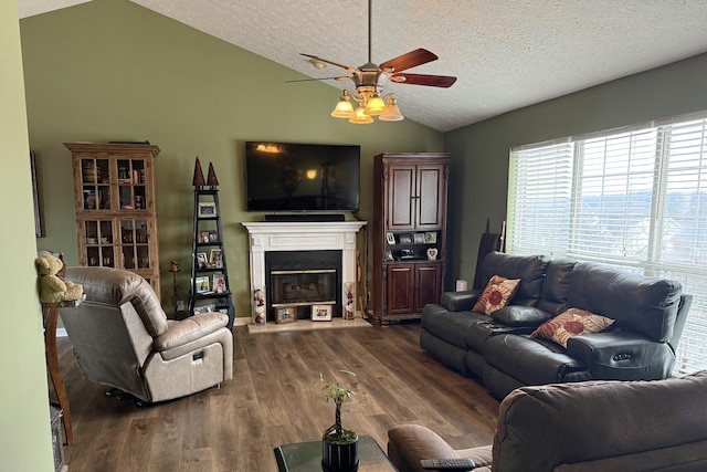 living room featuring dark wood-type flooring, ceiling fan, vaulted ceiling, and a textured ceiling