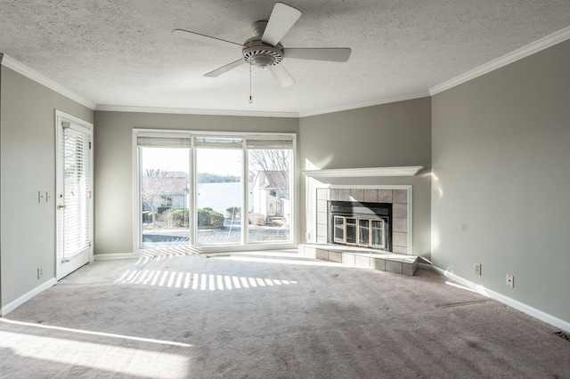 unfurnished living room with a tile fireplace, carpet, ornamental molding, and a textured ceiling