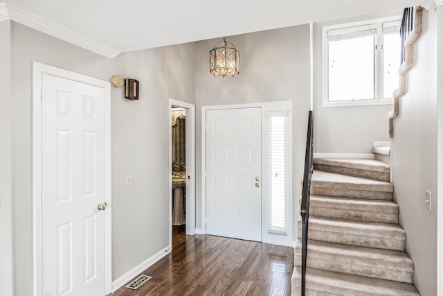 entrance foyer featuring crown molding, dark hardwood / wood-style flooring, and a textured ceiling