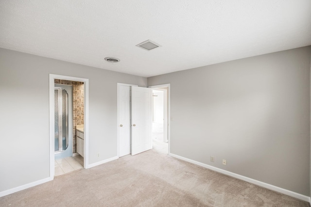 unfurnished bedroom featuring ensuite bath and light colored carpet