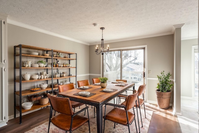 dining space featuring ornamental molding, a chandelier, hardwood / wood-style floors, and a textured ceiling