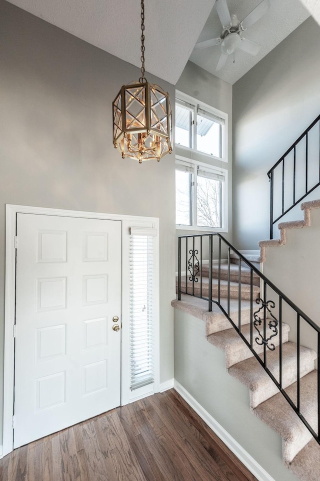 foyer with ceiling fan with notable chandelier and dark hardwood / wood-style floors