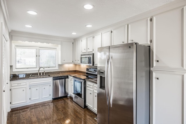 kitchen featuring sink, appliances with stainless steel finishes, ornamental molding, white cabinets, and dark hardwood / wood-style flooring