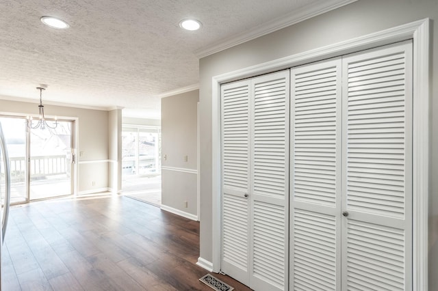 corridor featuring crown molding, dark hardwood / wood-style floors, a notable chandelier, and a textured ceiling