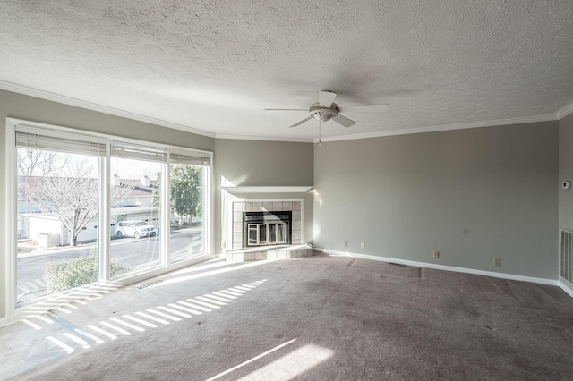 unfurnished living room featuring a tile fireplace, ceiling fan, carpet floors, ornamental molding, and a textured ceiling