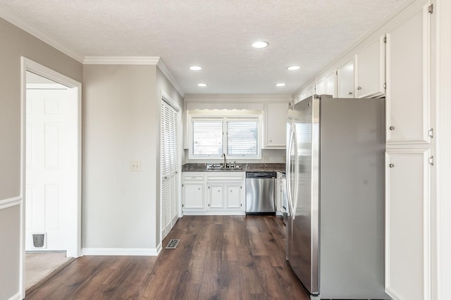 kitchen featuring appliances with stainless steel finishes, white cabinetry, sink, dark wood-type flooring, and a textured ceiling