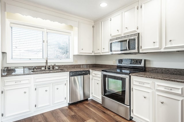 kitchen with sink, dark stone countertops, white cabinets, dark hardwood / wood-style flooring, and stainless steel appliances