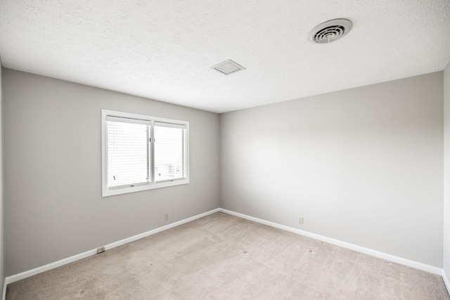 unfurnished room featuring light colored carpet and a textured ceiling