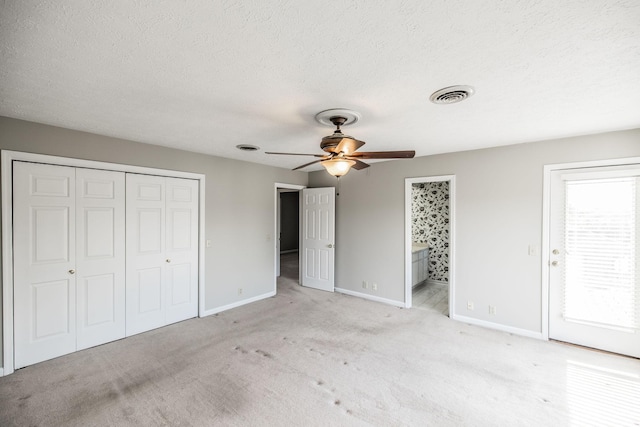 unfurnished bedroom featuring light carpet, multiple windows, ceiling fan, and ensuite bathroom