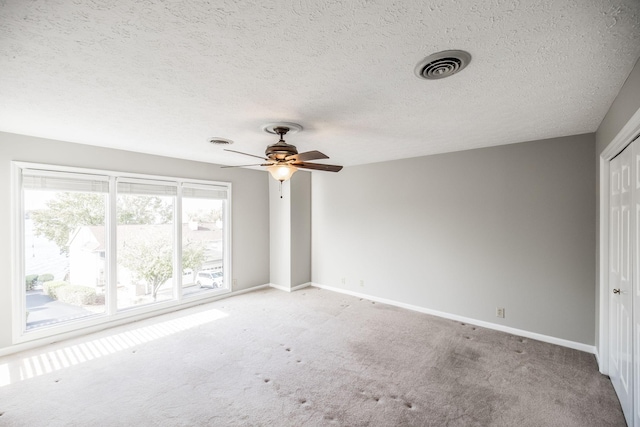 unfurnished bedroom featuring light carpet, a textured ceiling, and ceiling fan