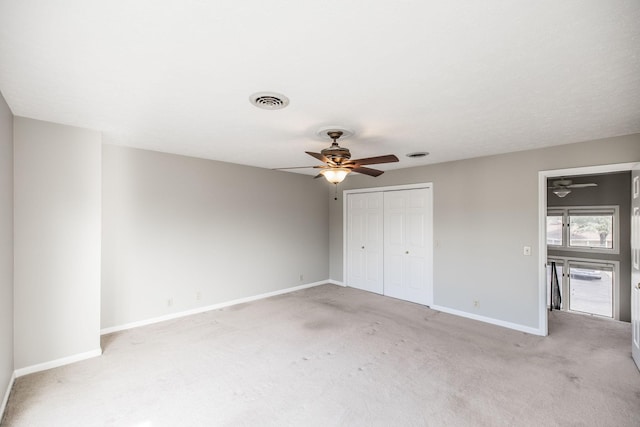 unfurnished bedroom featuring light carpet, ceiling fan, and a closet