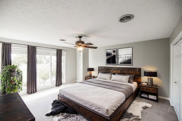 carpeted bedroom with access to outside, a textured ceiling, and ceiling fan