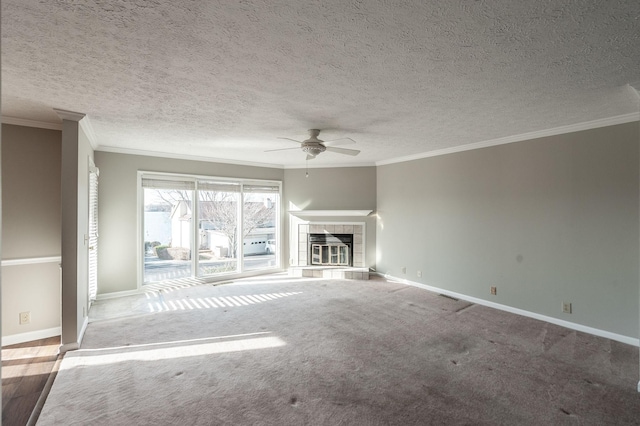 unfurnished living room featuring a textured ceiling, ornamental molding, carpet flooring, ceiling fan, and a fireplace