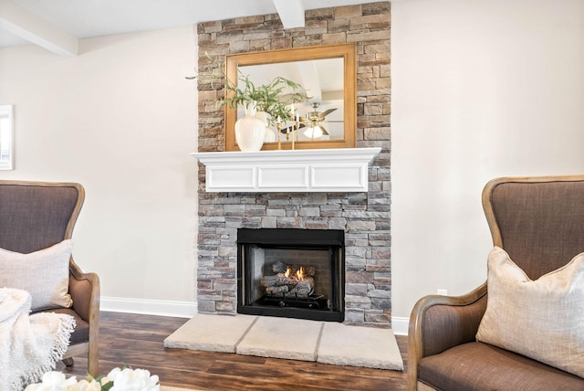 sitting room featuring dark hardwood / wood-style flooring, a stone fireplace, and beam ceiling