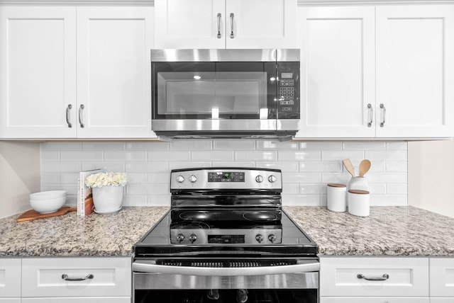 kitchen featuring white cabinetry, light stone counters, decorative backsplash, and appliances with stainless steel finishes