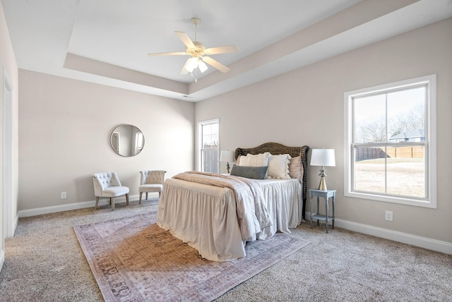 carpeted bedroom with a tray ceiling and ceiling fan