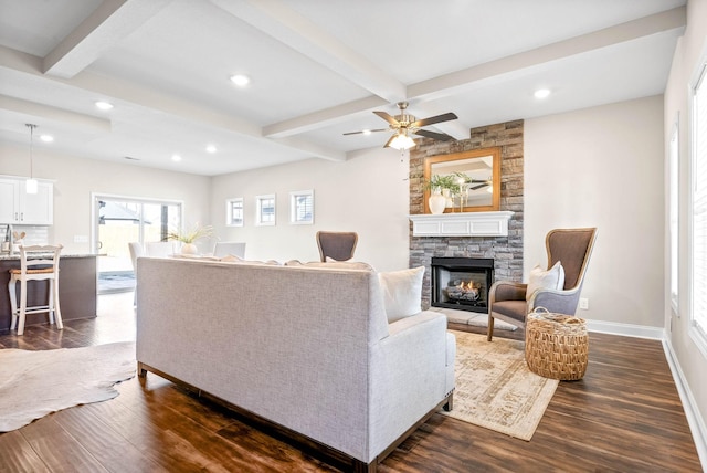 living room featuring beamed ceiling, ceiling fan, dark hardwood / wood-style floors, and a fireplace