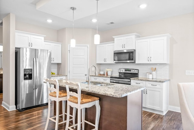 kitchen with sink, white cabinetry, decorative light fixtures, a center island with sink, and appliances with stainless steel finishes