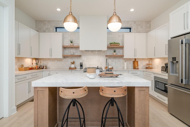 kitchen with light stone counters, appliances with stainless steel finishes, an island with sink, and white cabinets