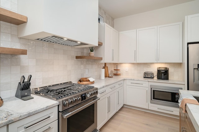 kitchen with stainless steel appliances, white cabinets, and premium range hood