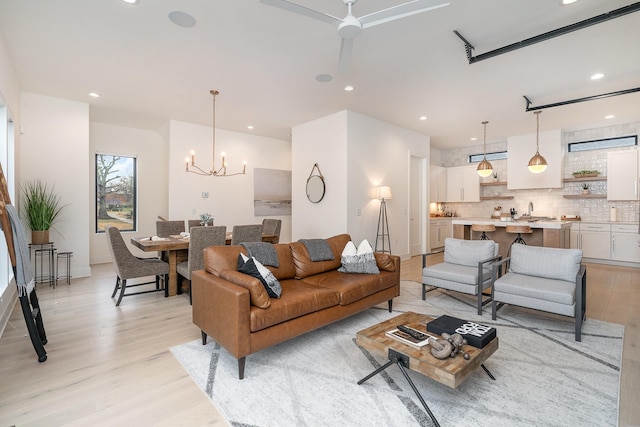 living room featuring an inviting chandelier, sink, and light hardwood / wood-style floors