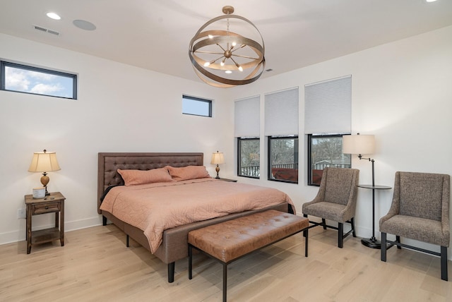 bedroom featuring multiple windows, a chandelier, and light wood-type flooring