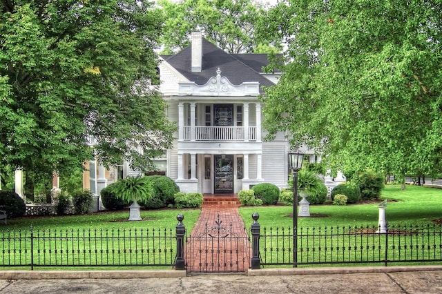 view of front of property featuring a balcony and a front yard