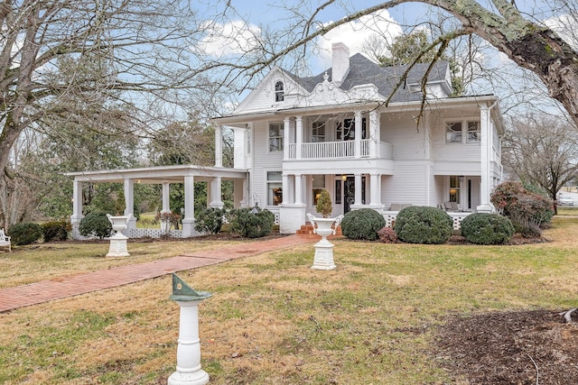 greek revival inspired property with a balcony and a front lawn