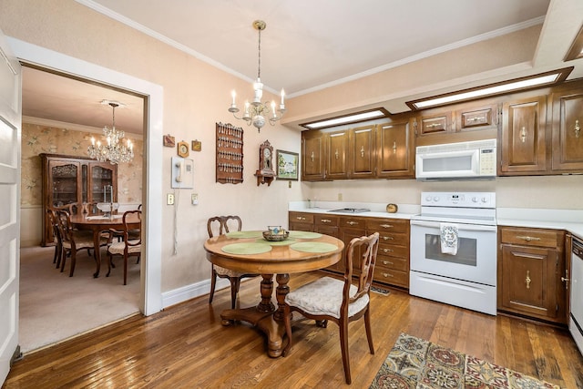 kitchen with pendant lighting, white appliances, ornamental molding, and an inviting chandelier