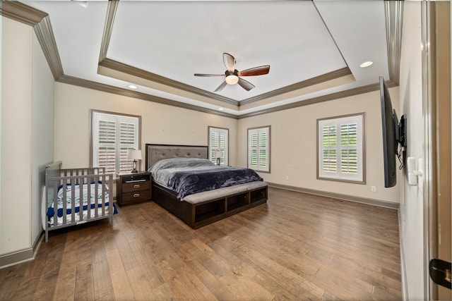 bedroom with crown molding, ceiling fan, a raised ceiling, and hardwood / wood-style floors