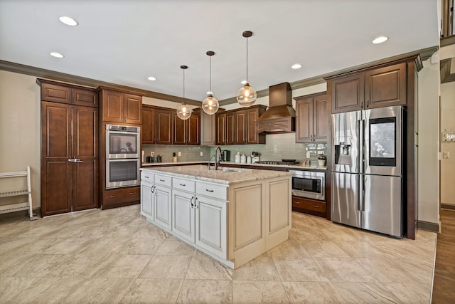 kitchen featuring premium range hood, appliances with stainless steel finishes, sink, hanging light fixtures, and a kitchen island with sink