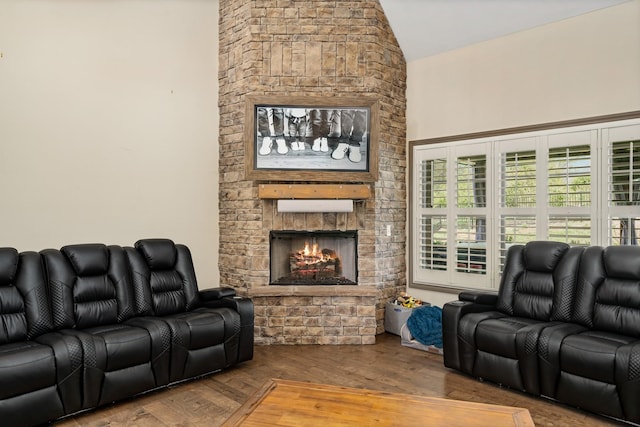 living room with lofted ceiling, a stone fireplace, and wood-type flooring