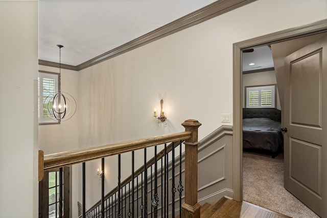 hallway with ornamental molding, a wealth of natural light, and a notable chandelier